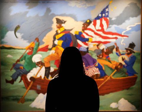 (FILES) In this file photo taken on May 04, 2021, woman poses in front of Robert Colescott's "George Washington Carver Crossing the Delaware: Page from an American History Textbook" during a press preview for Sotheby�s Impressionist & Modern Art Evening Sale Live Auction: May 12, 2021, in New York. - Black artists are represented like never before at New York's spring sales next week after years of being overlooked and underappreciated, with several expected to set new records for their works. American-born Jean-Michel Basquiat, of Haitian and Puerto Rican descent, becomes the first Black painter to headline both Christie's and Sotheby's main auctions, on May 11 and 12, 2021, respectively.