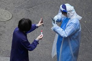 Un trabajador con traje protector verifica el código QR en el teléfono de un residente para realizar pruebas de ácido nucleico durante el encierro, en medio de la pandemia de la enfermedad por coronavirus, en Shanghái, China, el 26 de abril de 2022. Foto REUTERS/Aly Song