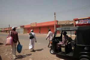 La gente pasa frente a las tiendas cerradas en Jartum, Sudán, el lunes 17 de abril de 2023.