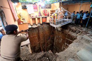 Un oficial de policía usa su teléfono móvil para tomar fotografías durante una operación de rescate después de que el techo de un pozo en un complejo de templos se derrumbara en la ciudad central de Indore, India, el 31 de marzo de 2023.