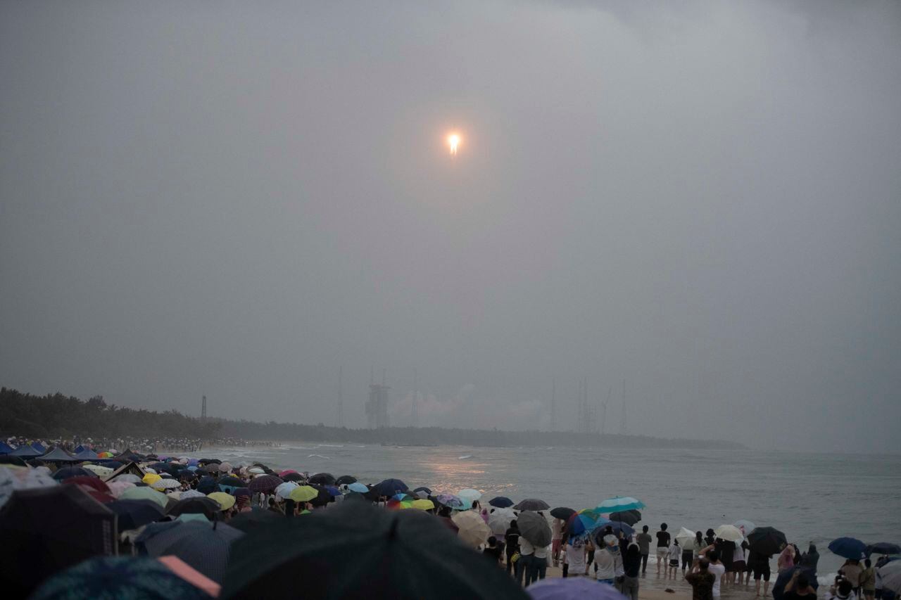 Una multitud observa desde una playa cómo un cohete Gran Marcha 5, que transporta la sonda lunar de la misión Chang'e-6.