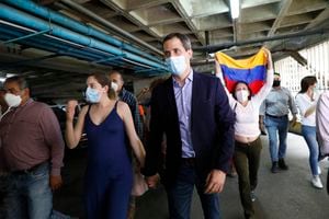 El líder opositor Juan Guaidó y su esposa, Fabiana Rosales, caminan en el estacionamiento del edificio residencial en el que viven luego de que encapuchados intentaran retener al opositor, el lunes 12 de julio de 2021. (AP Foto/Ariana Cubillos)
