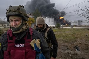Un miembro del servicio de rescate ucraniano y un soldado inspeccionan el área mientras se eleva humo negro después de un ataque a una reserva de petróleo en Kherson el 20 de noviembre de 2022, en medio de la invasión rusa de Ucrania. (Foto de BULENT KILIC / AFP)