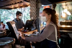 Portrait of a woman working at the cashier at a restaurant wearing a facemask - food service occupation concepts