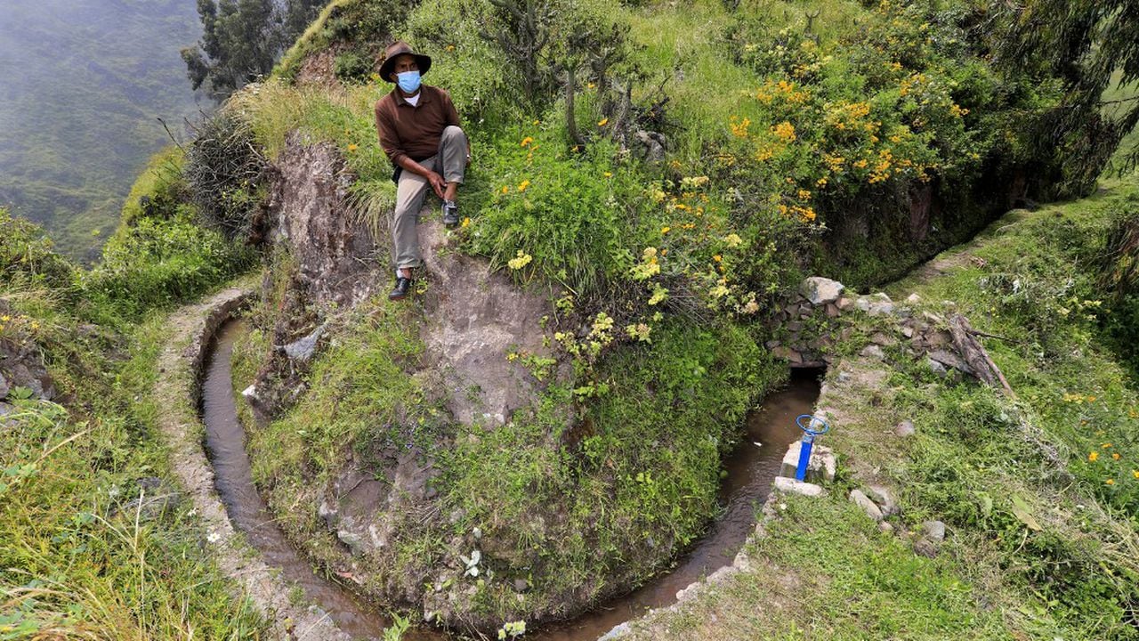 Foto difundida por la organización Aquafondo. Aparece un campesino sentado junto a parte de una red prehispánica de canales de piedra que surca las laderas de los cerros transportando agua para la agricultura, en San Pedro de Casta, provincia de Lima, Perú, el 18 de abril de 2021. Foto de Ivan Laiza / AQUAFONDO / AFP