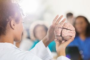 Vista posterior del profesor de la escuela de medicina afroamericana americana que enseña a los estudiantes sobre el cerebro humano.