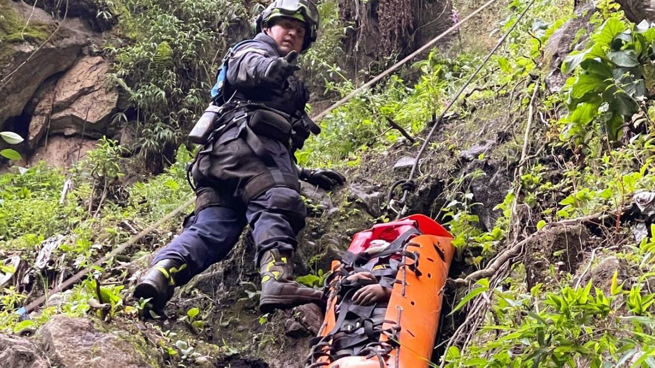 Un rescatista lleva el cuerpo de una de las personas que cayó a un barranco en Monserrate