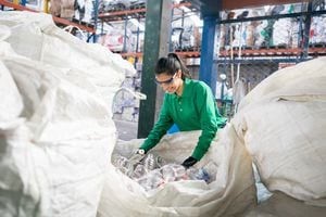 Mujer que trabaja en una fábrica de reciclaje clasificando algunas botellas y luciendo muy feliz - conceptos ambientales