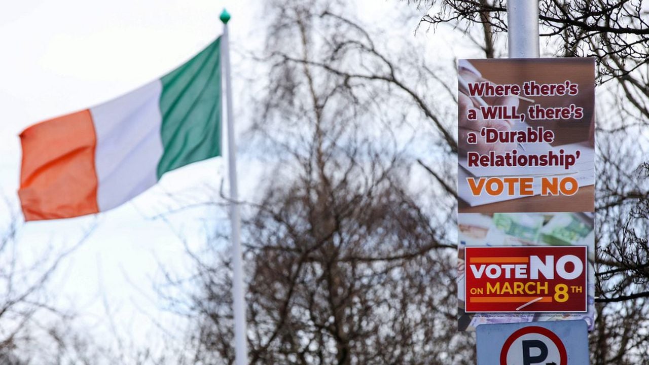 Se ven carteles de "No" en la calle frente a los edificios gubernamentales en Dublín, Irlanda, el 5 de marzo de 2024, antes del referéndum irlandés del viernes. Al fondo, la bandera del país. Irlanda se prepara para votar el viernes sobre las referencias constitucionales a la familia y el papel de la mujer en el hogar (Foto de PAUL FE / AFP)