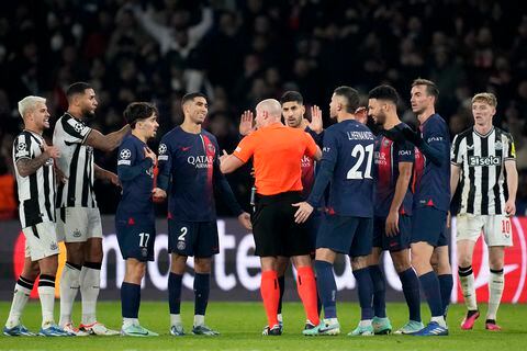 Los jugadores del PSG rodean al árbitro Szymon Marciniak al reclamar un penal en el partido contra Newcastle en la Liga de Campeones, el martes 28 de noviembre de 2023, en París. (AP Foto/Christophe Ena)