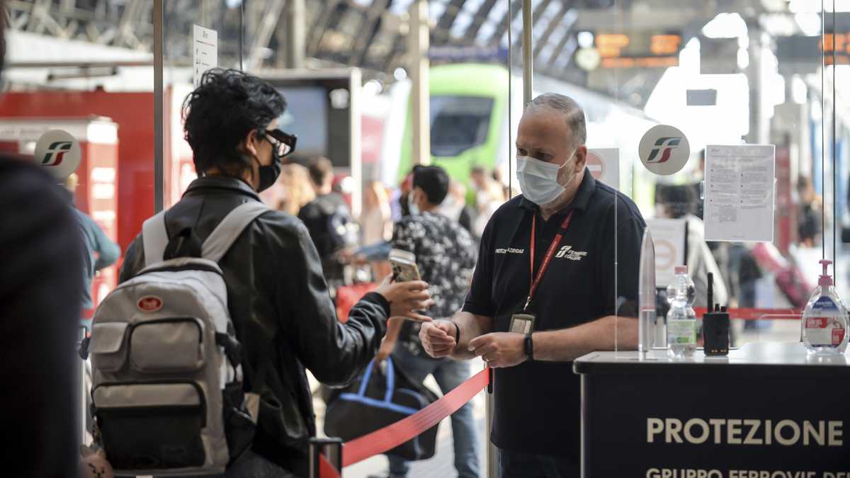 Un pasajero sostiene su teléfono en un punto de control en la estación de tren Stazione Centrale de Milán, Italia. (Claudio Furlan / LaPresse vía AP)