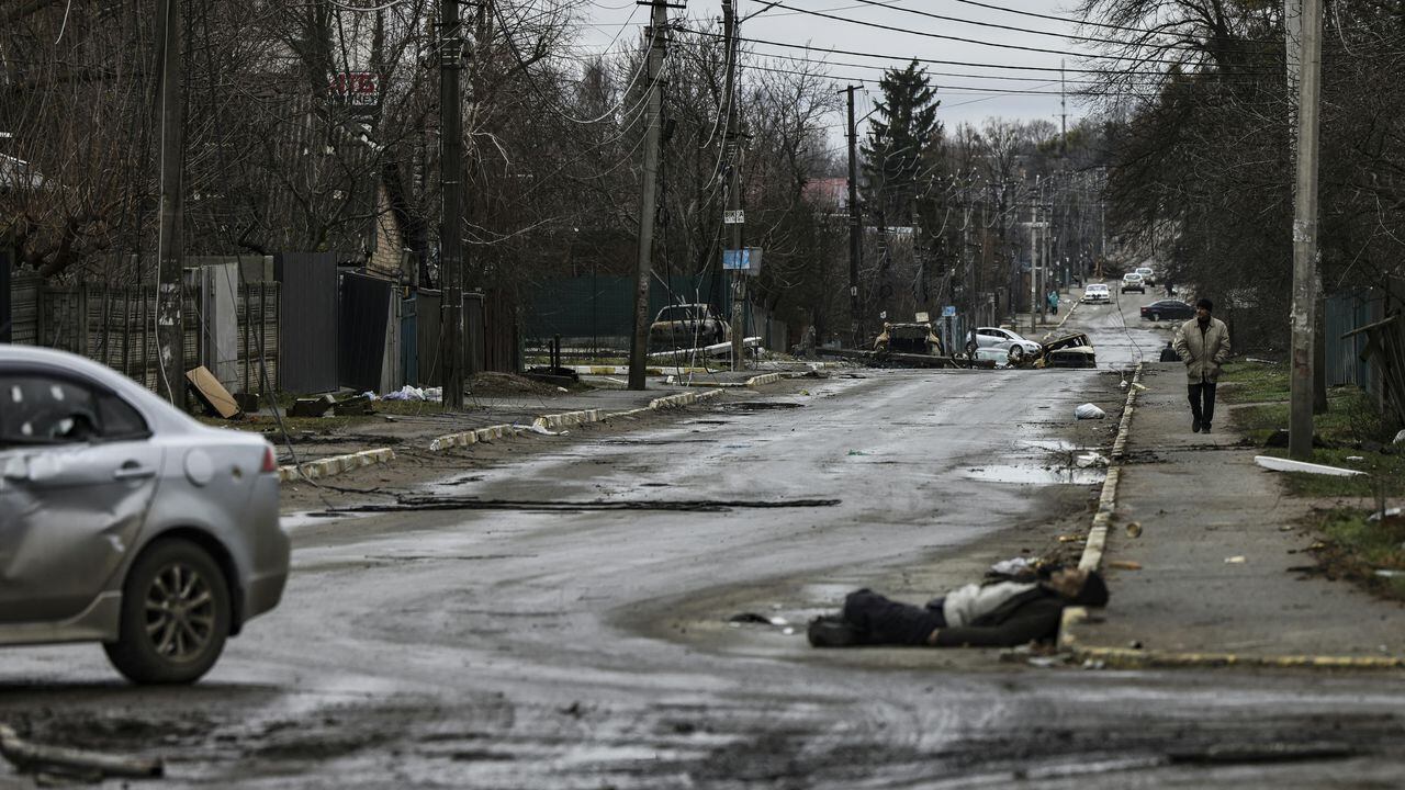 EDITORS NOTE: Graphic content / A man walks on a street with several dead bodies on the ground a street in Bucha, northwest of Kyiv, as Ukraine says Russian forces are making a "rapid retreat" from northern areas around Kyiv and the city of Chernigiv, on April 2, 2022. - The bodies of at least 20 men in civilian clothes were found lying in a single street Saturday after Ukrainian forces retook the town of Bucha near Kyiv from Russian troops, AFP journalists said. Russian forces withdrew from several towns near Kyiv in recent days after Moscow's bid to encircle the capital failed, with Ukraine declaring that Bucha had been "liberated". (Photo by RONALDO SCHEMIDT / AFP)