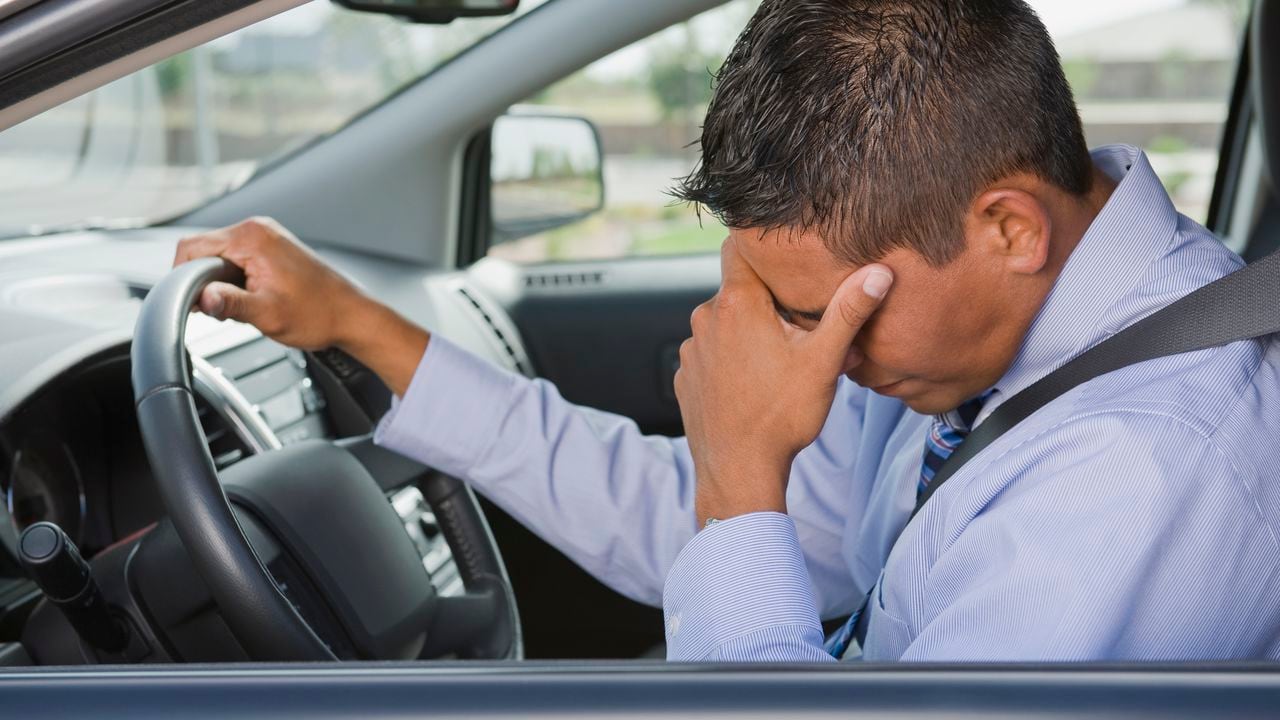 Frustrated Hispanic businessman driving in traffic