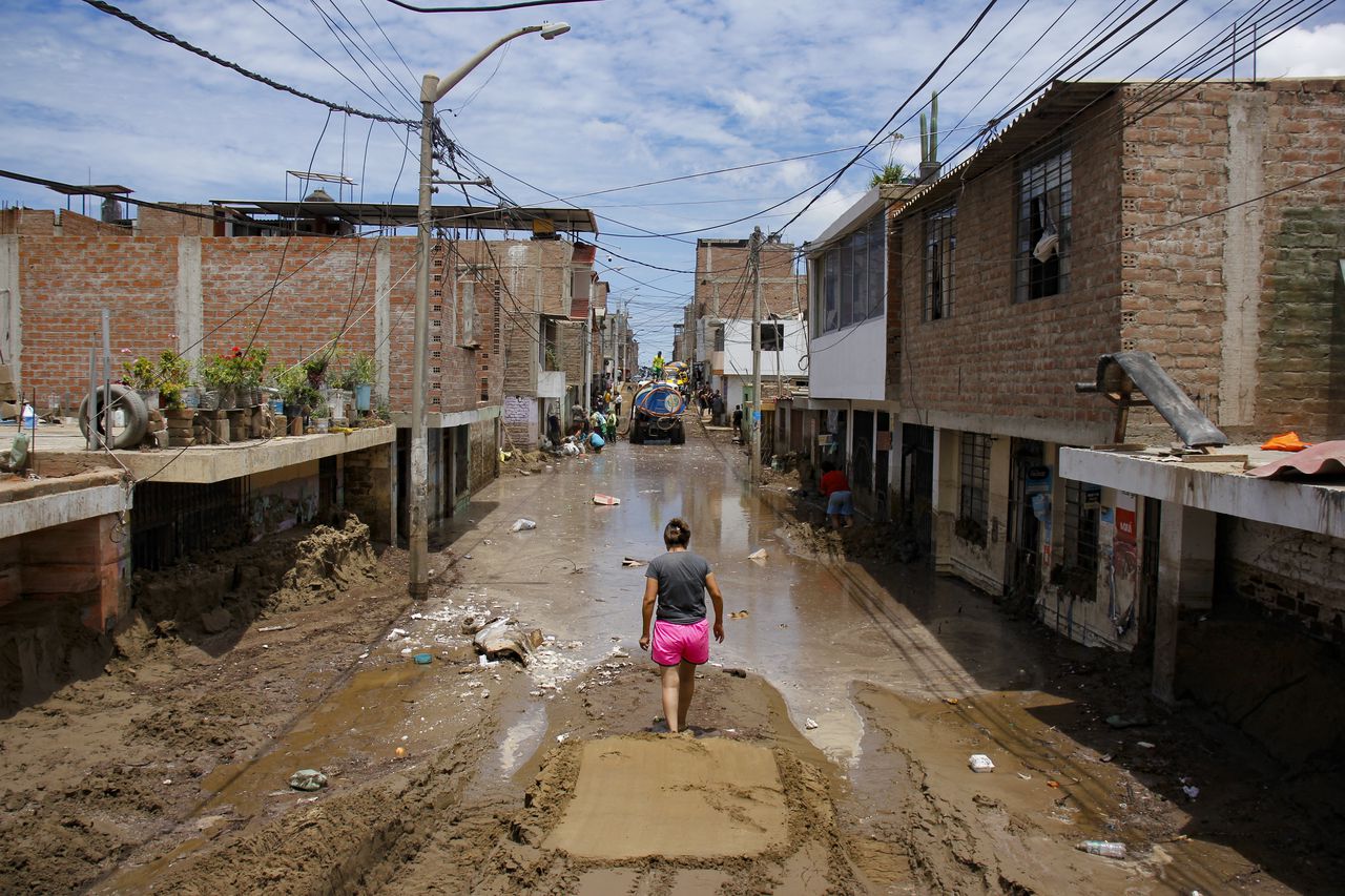 Un residente de La Esperanza, al norte de Trujillo en el Departamento de La Libertad, Perú, camina por una calle inundada -también cubierta de lodo y arena luego de fuertes lluvias provocadas por el ciclón Yaku. (Foto por Arturo GUTARRA / AFP)
