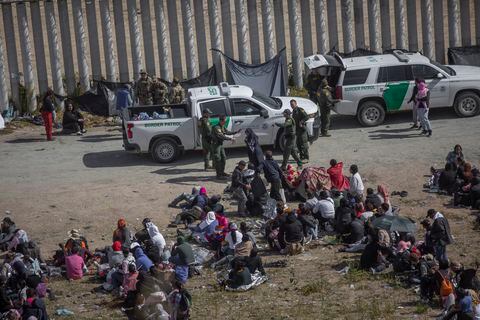 Los migrantes se sientan en filas frente a las fuerzas de seguridad estadounidenses en el área entre los dos muros que separan a México de los Estados Unidos.