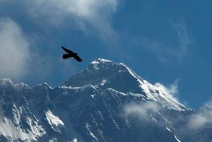 FILE - A bird flies with Mount Everest seen in the background from Namche Bajar, Solukhumbu district, Nepal, May 27, 2019. As the mountaineering community prepare to celebrate the 70 anniversary of the conquest of Mount Everest, there is rising concern about the glacier and snow is melting, the temperature is rising and weather is getting harsh and unpredictable on world's highest mountain. (AP Photo/Niranjan Shrestha, File)