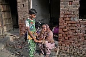 Un niño cristiano consuela a una mujer que llora tras ver su casa destrozada por una turba en Jaranwala, en el distrito de Faisalabad, Pakistán, el jueves 17 de agosto de 2023. La policía detuvo a más de 100 musulmanes en redadas durante la noche en el este de Pakistán, donde una turba de musulmanes enojados por la supuesta profanación de un Corán por parte de un hombre cristiano atacó iglesias y viviendas de la minoría cristiana. (AP Foto/K.M. Chaudary)