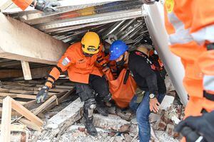 Rescatistas sacan a un herido debajo de un edificio derrumbado por el terremoto en Indonesia.