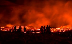 La gente observa cómo fluye lava de la erupción de un volcán en la península de Reykjanes en el suroeste de Islandia. La última erupción volcánica de Islandia atrae rápidamente a multitudes de personas que esperan acercarse a los suaves flujos de lava. Foto: AP / Marco Di Marco.