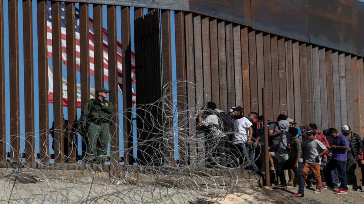 Migrantes centroamericanos miran a través de la valla cerca del cruce fronterizo de El Chaparral en Tijuana, México. Foto: AFP
