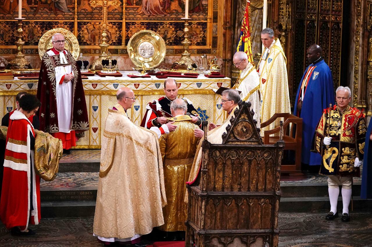 El príncipe William le pone una túnica al rey Carlos III durante su ceremonia de coronación en la Abadía de Westminster