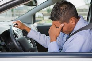 Frustrated Hispanic businessman driving in traffic