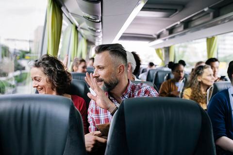 Una pareja madura sentada en un autobús saluda a sus amigos cuando se van.