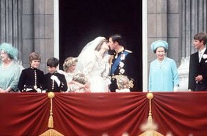 El príncipe Carlos y la princesa Diana se besan en el balcón del Palacio de Buckingham, el 29 de julio de 1981. Están rodeados por sus damas de honor y pajes, así como por la reina Isabel II, el príncipe Eduardo y la reina madre. (Foto de Tim Graham Photo Library a través de Getty Images)