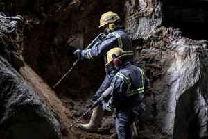 Dos trabajadores con casco y traje de protección mediante taladradoras en un entorno subterráneo