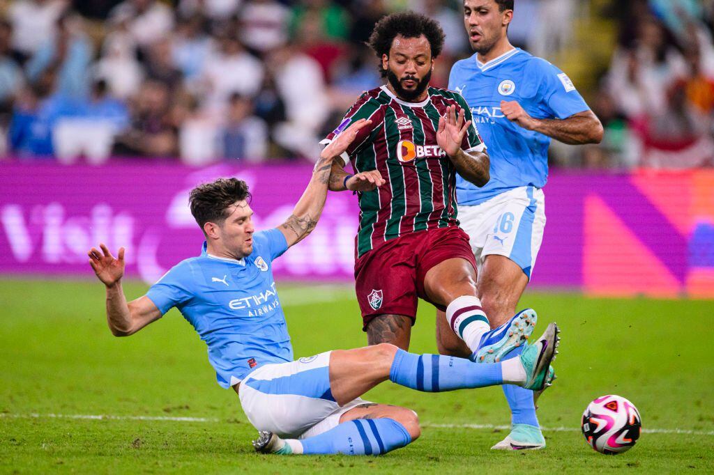 JEDDAH, SAUDI ARABIA - DECEMBER 22: Marcelo Vieira of Fluminense (R) is challenged by John Stones of Manchester City (L) during the FIFA Club World Cup Final match between Manchester City and Fluminense at King Abdullah Sports City on December 22, 2023 in Jeddah, Saudi Arabia. (Photo by Marcio Machado/Eurasia Sport Images/Getty Images)