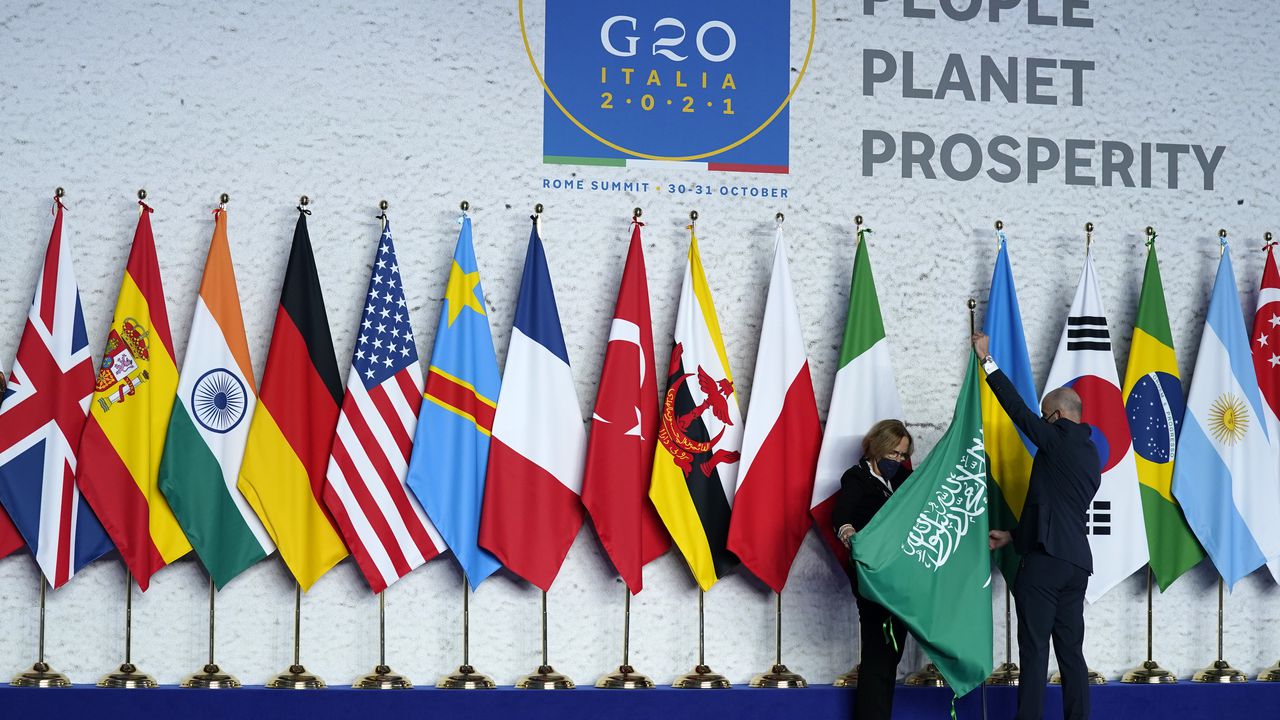 Operarios ajustan la bandera de Arabia Saudí antes de una foto grupal al inicio de la cumbre del G20 en Roma, el 30 de octubre de 2021. (AP Foto/Evan Vucci, Pool)