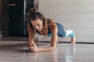 Fit woman doing plank exercise, workout at home.