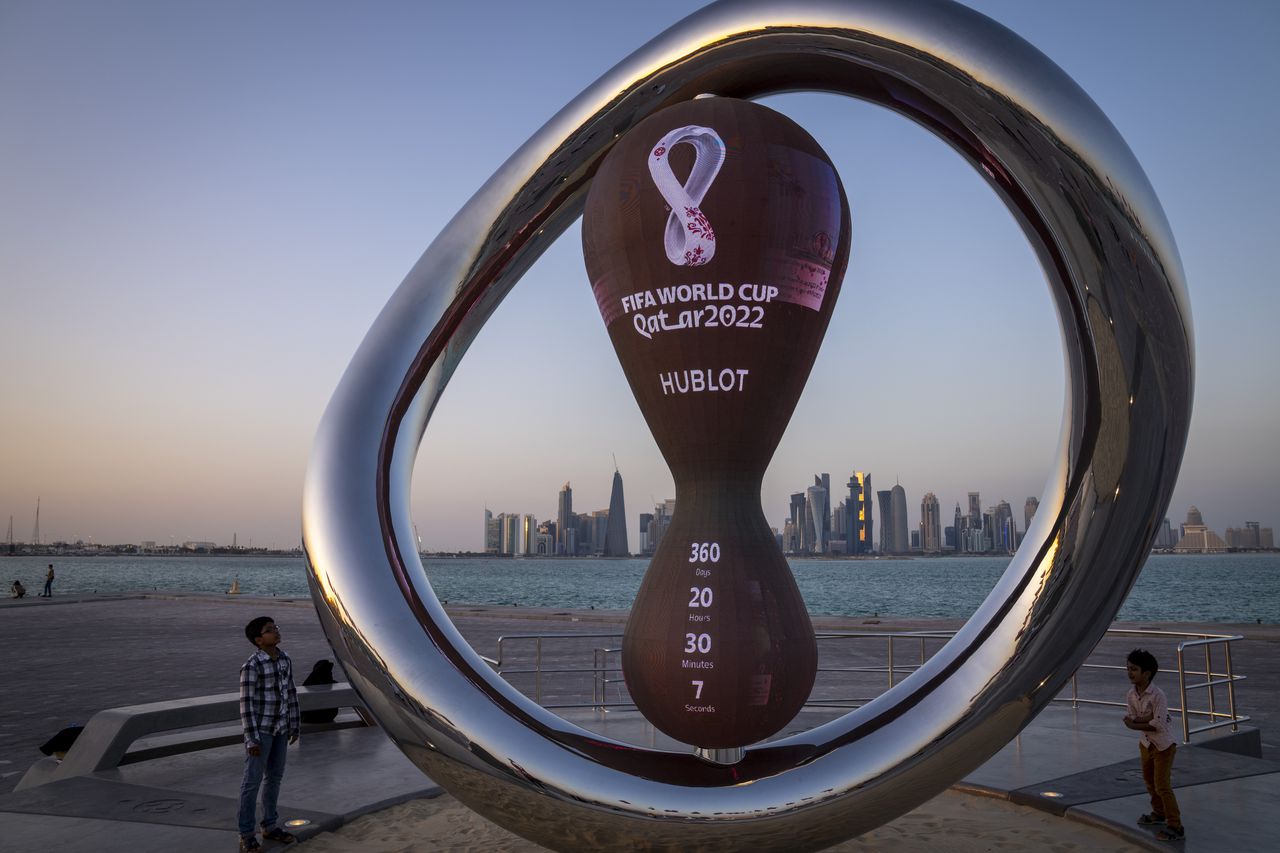 Children stand next to the official countdown clock showing remaining time until the kick-off of the World Cup 2022, in Doha, Qatar, Thursday, Nov. 25, 2021. The World Cup is due to start in November 2022. (AP Photo/Darko Bandic)