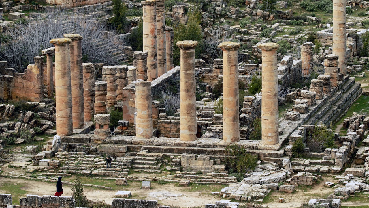 Una mujer pasa junto a las ruinas del Templo de Apolo en la antigua ciudad de Cirene, en el este de Libia, en la región de Jabal al-Akhdar. Imagen de archivo.