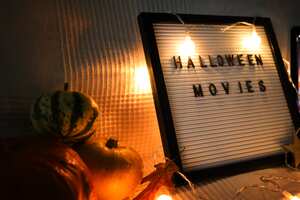letter board on sofa with pumpkins and garland . Halloween movie .pumpkins ,close up , flat lay autumn decoration