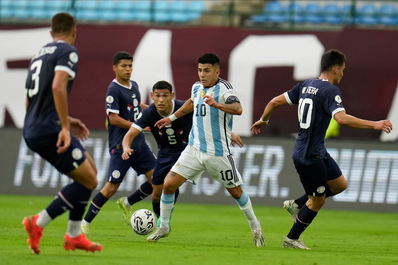 El argentino Thiago Almada, centro, controla el balón perseguido por el paraguayo Gilberto Flores (5) durante el partido de fútbol del torneo preolímpico sudamericano sub-23 en el estadio Brígido Iriarte de Caracas, Venezuela, el jueves 8 de febrero de 2024. (AP Foto/ Matías Delacroix)
