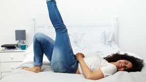 Woman lying on bed laughing