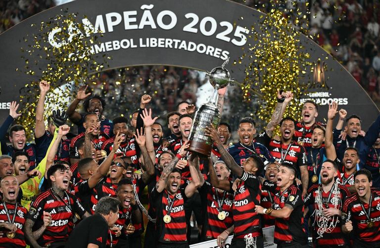 El delantero #27 del Flamengo, Bruno Henrique (D), y el mediocampista uruguayo #10 Giorgian de Arrascaeta (I) levantan el trofeo con sus compañeros de equipo después de ganar el partido final de la Copa Libertadores de Brasil.