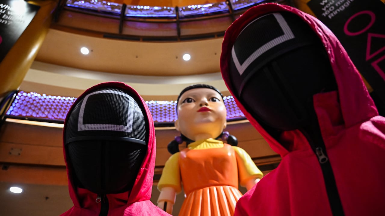 Cosplayers vestidos con atuendos de la serie de Netflix "El Juego del Calamar" junto a una estatua de muñeca en un centro comercial en Kuala Lumpur el 20 de octubre de 2021. (Photo by MOHD RASFAN / AFP)
