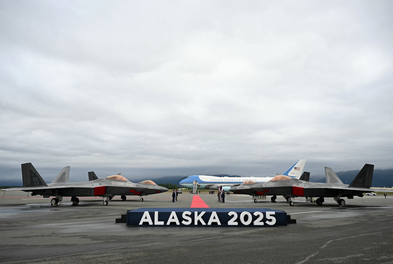 Se ven aviones de combate F-22 en la pista con el Air Force One en la distancia después de que el presidente estadounidense Donald Trump aterrizara en la base conjunta Elmendorf-Richardson en Anchorage, Alaska, el 15 de agosto de 2025. El presidente estadounidense Donald Trump aterrizó en la base militar de Alaska para una cumbre muy esperada con su homólogo ruso Vladimir Putin para presionar para que se ponga fin a la sangrienta guerra de Moscú en Ucrania
