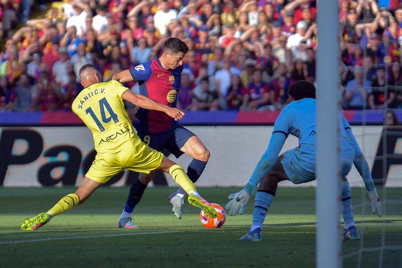 El centrocampista español #14 del Villarreal, Santi Comesana, y el delantero polaco #09 del Barcelona, Robert Lewandowski, compiten por el balón.