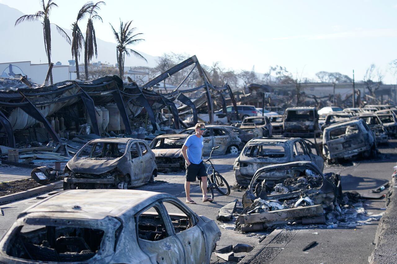 Un hombre camina entre automóviles carbonizados por un incendio forestal el viernes 11 de agosto de 2023, en Lahaina, Hawai. (AP Foto/Rick Bowmer)