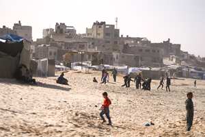 Niños juegan en la arena en un campamento para palestinos desplazados internos frente a la playa en Deir al-Balah, en el centro de la Franja de Gaza.