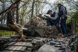 El periodista visual de la AFP Arman Soldin (2do der.) se sienta en un tanque militar ucraniano durante una entrevista con un soldado, junto con el reparador Oleksiy Obolensky (der) en la región de Donbass el 29 de abril de 2022.