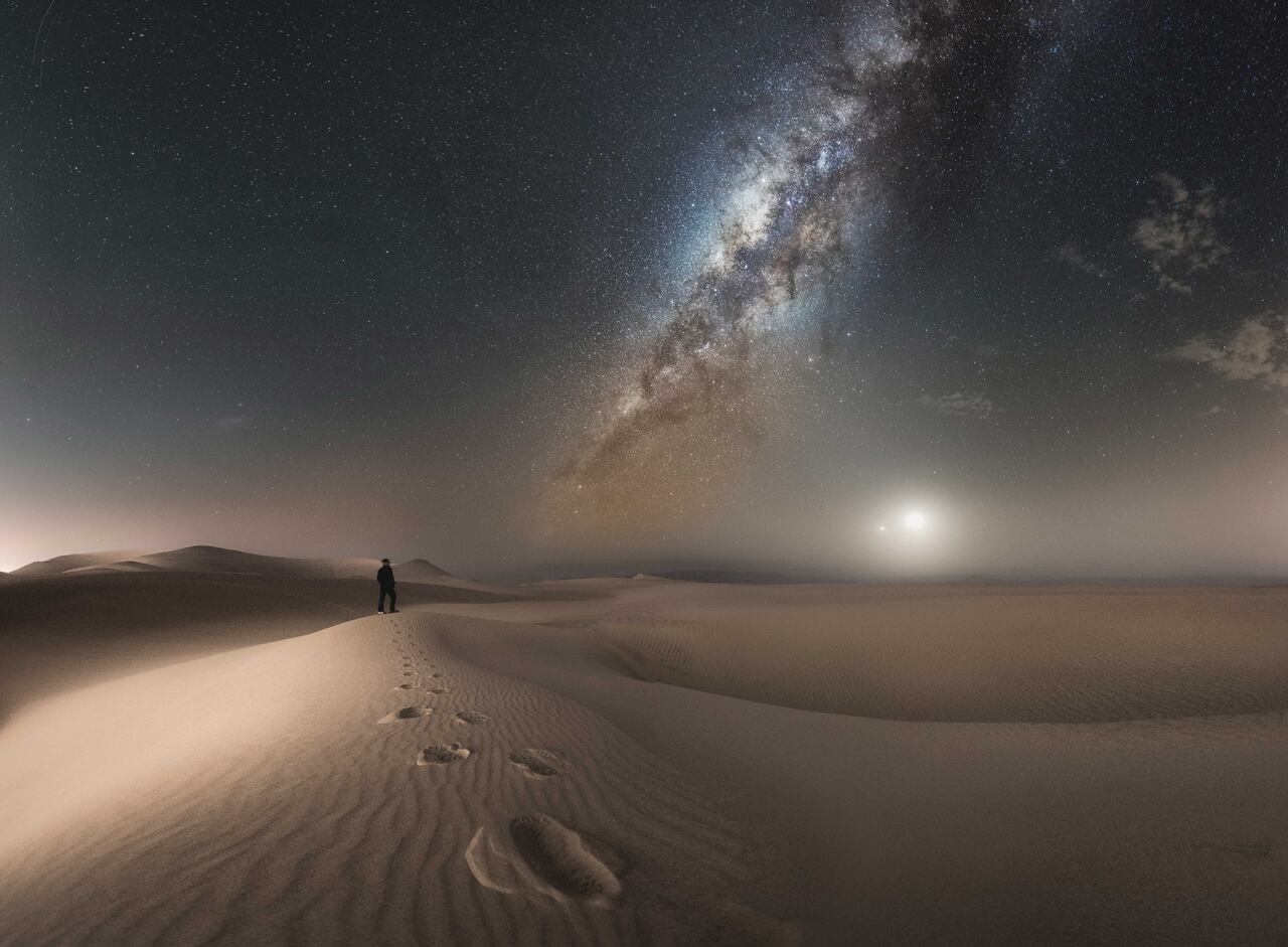 La NASA describió esta foto como “una hermosa conjunción de Venus y la Luna, un ser humano, arena y la Vía Láctea”. 2016 / Ica, Perú,