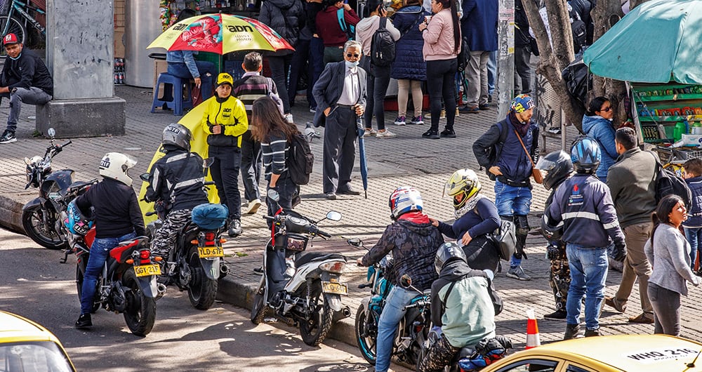 Mototaxistas haciendo fila a la salida de una estación de Transmilenio para recoger pasajeros.