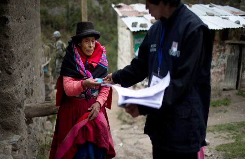 Una indígena Quechua le entrega su identificación a un oficial electoral durante las votaciones presidenciales en Iquicha, Perú. 