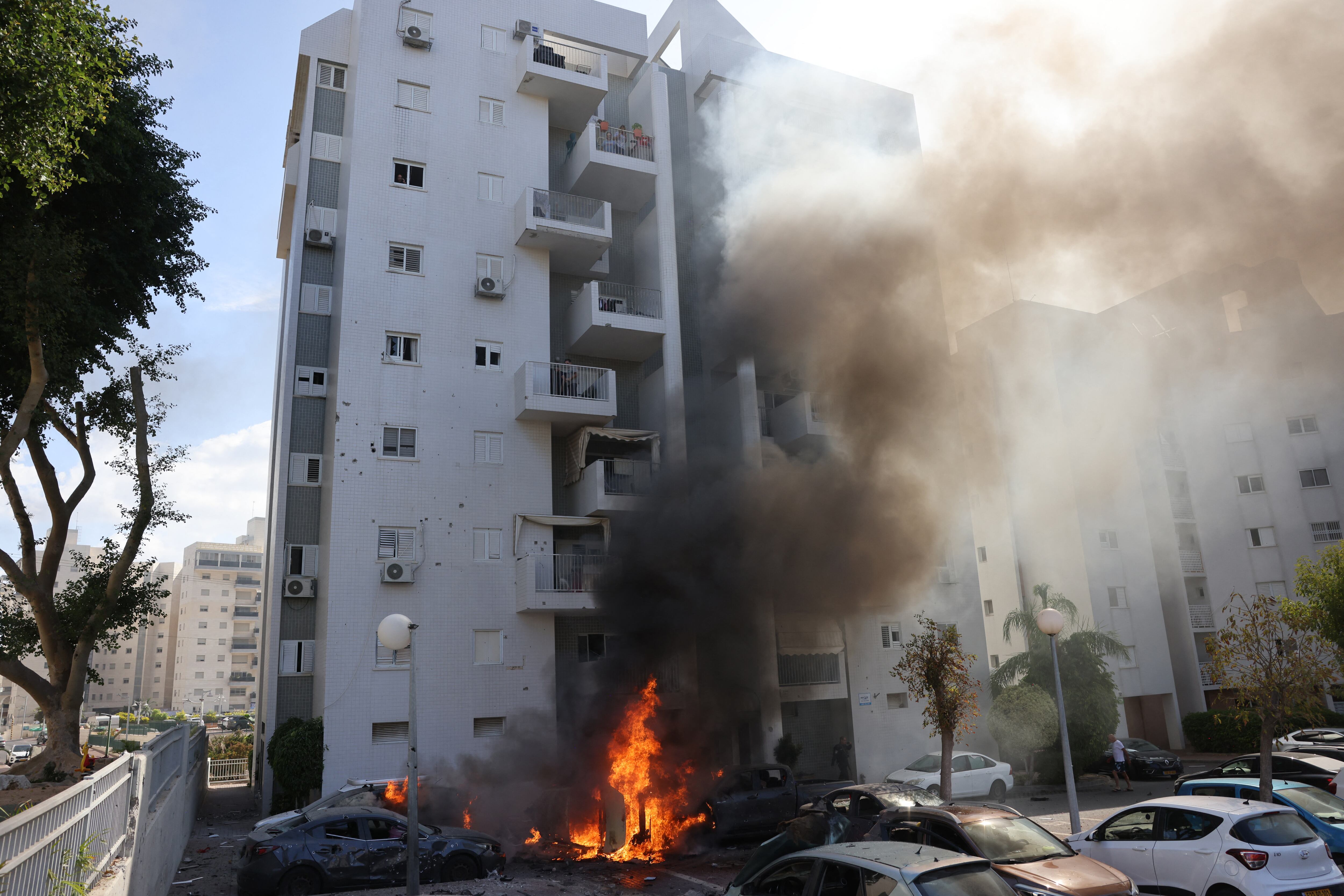 Automóviles estacionados afuera de un edificio residencial se incendian durante un ataque con cohetes desde la Franja de Gaza hacia la ciudad sureña israelí de Ashkelon el 7 de octubre de 2023. El ministro de Defensa del país afirmó el 7 de octubre que militantes palestinos han iniciado una "guerra" contra Israel después de una ráfaga de cohetes y la infiltración de combatientes desde el enclave palestino, lo que representa una escalada importante en el conflicto israelí-palestino. (Foto de AHMAD GHARABLI / AFP).