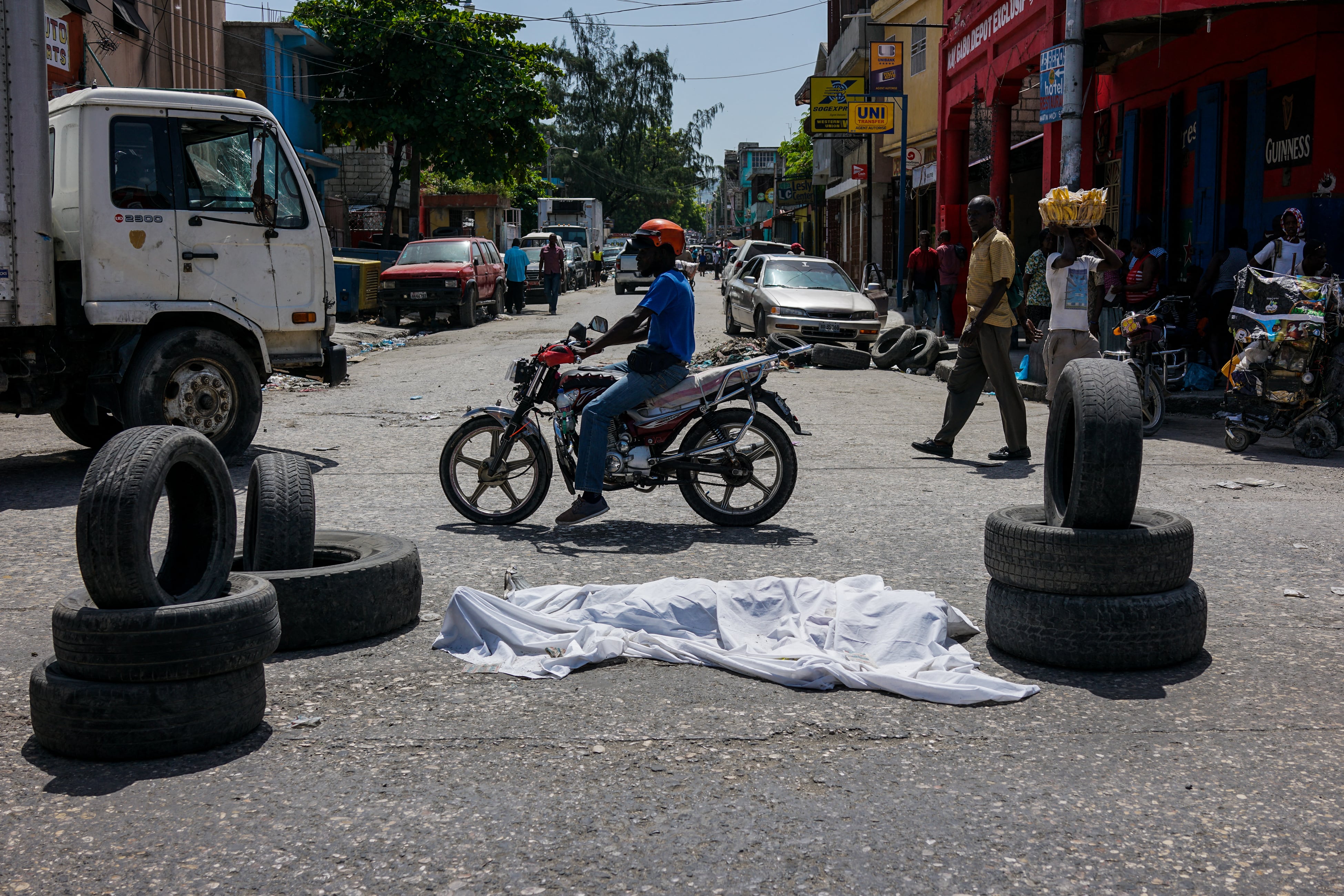 (FILES) In this file photo taken on August 26, 2019, dead body covered with a sheet lies on the middle of the road in downtown of Port-au-Prince. - Long confined to the slums, the gangs have gradually extended their control in Haiti and the nearly three million inhabitants of Port-au-Prince are forced to adapt their daily lives to this reality, for fear of being the next victim. "The gangs today reign supreme and lords over the country," laments G�d�on Jean, director of the Center for Analysis and Research in Human Rights, based in the Haitian capital. (Photo by CHANDAN KHANNA / AFP)