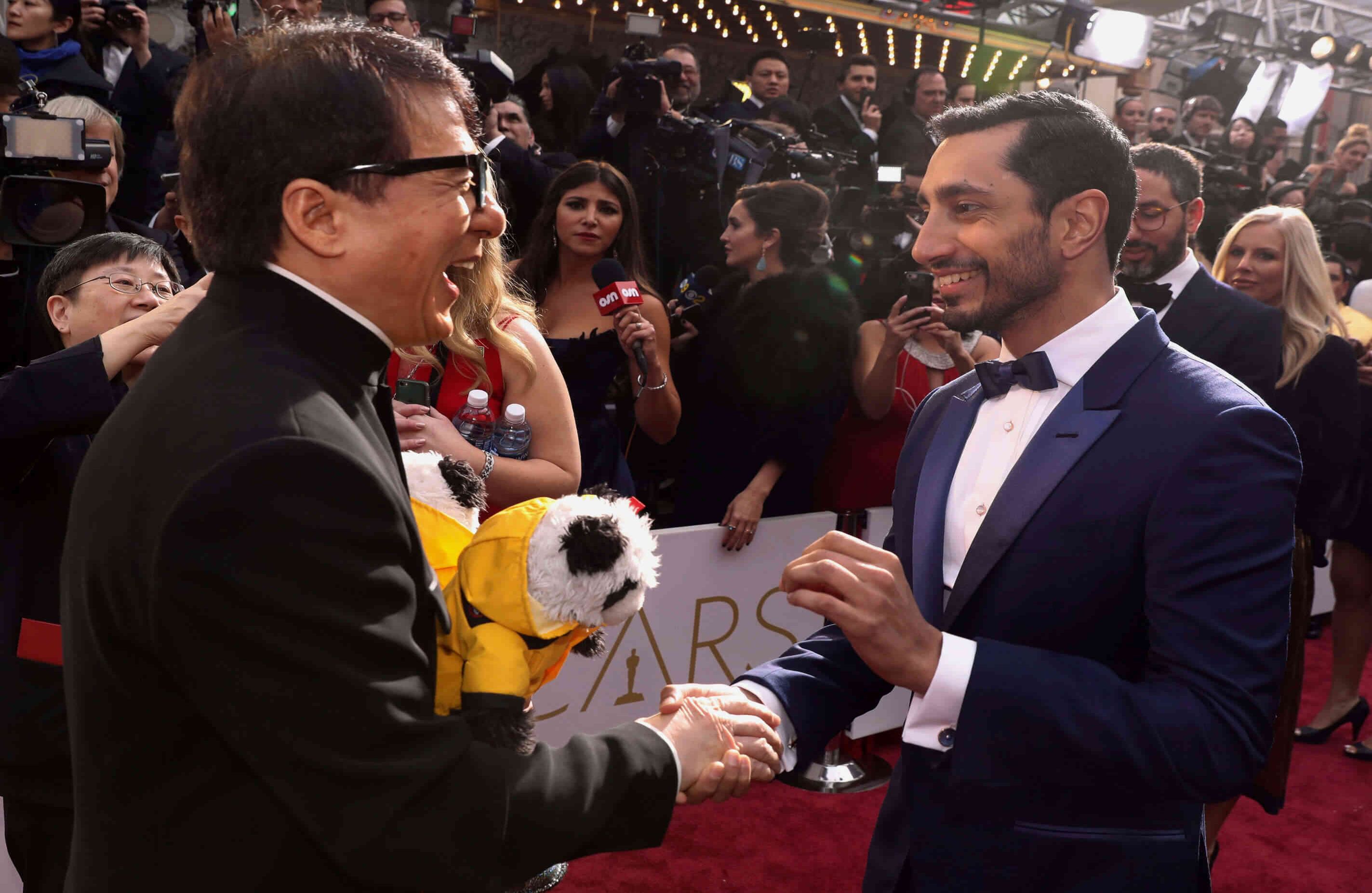 Jackie Chan saluda a Riz Ahmed, el actor chino llegó con dos pandas de peluche que tenían el logo de Unicef. El actor es embajador para la preservación de estos animales (Photo by Matt Sayles/Invision/AP)